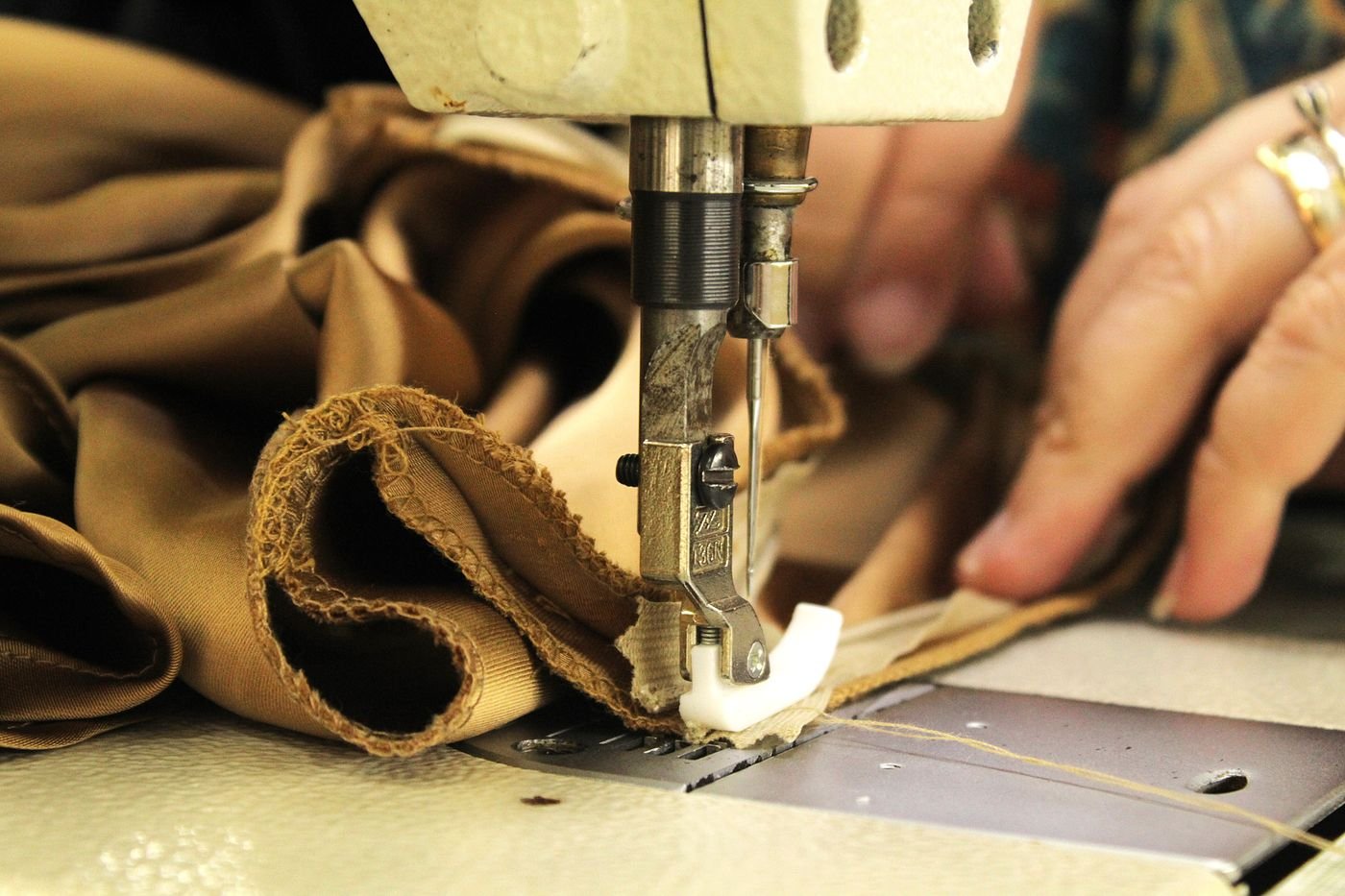 Sewing machine stitching a folded fabric edge